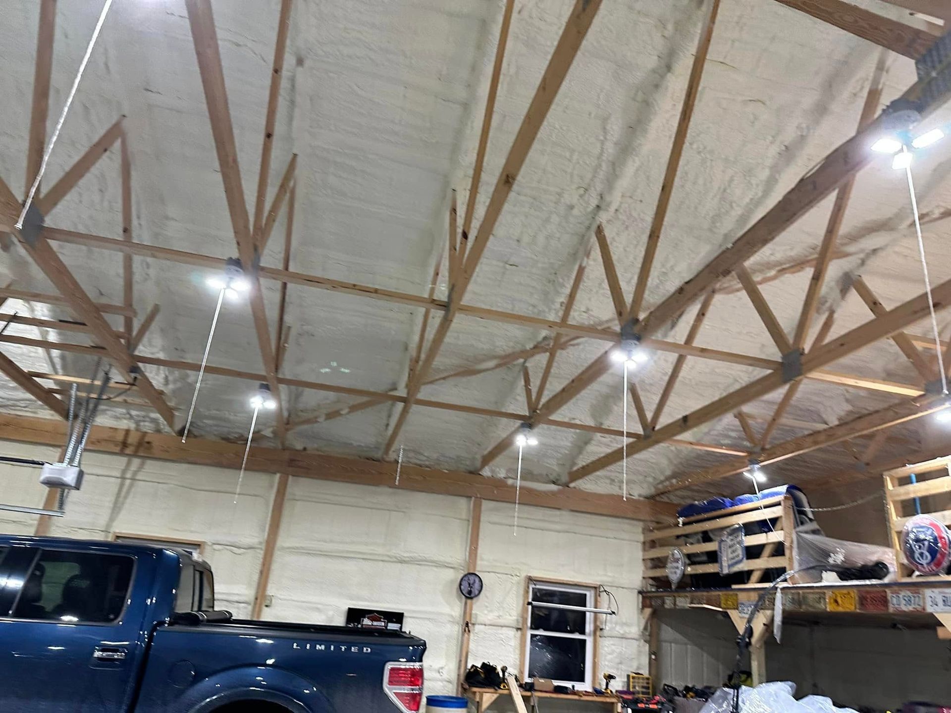A blue truck is parked in a garage with a wooden ceiling.