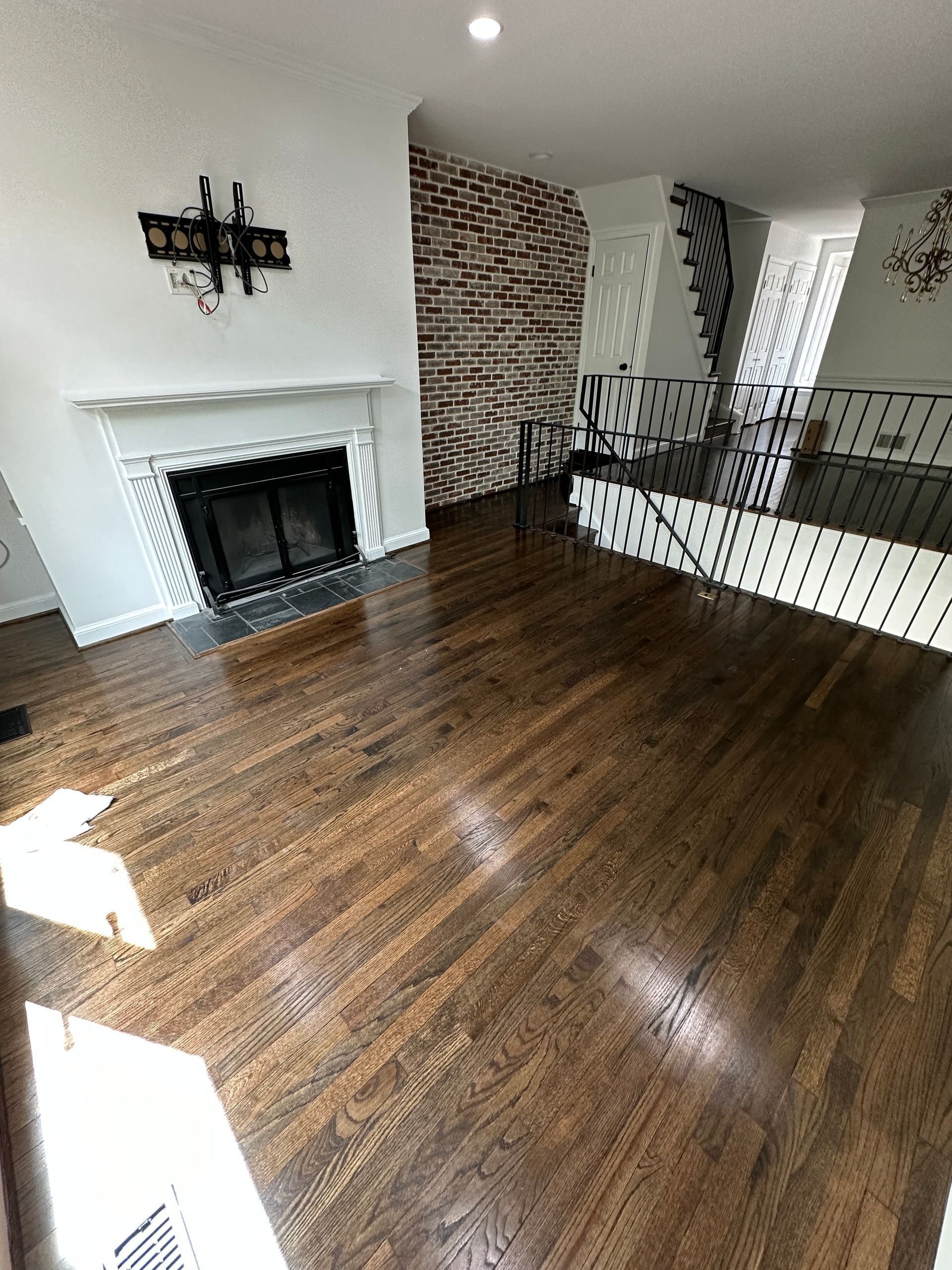 A living room with hardwood floors , a fireplace and stairs.