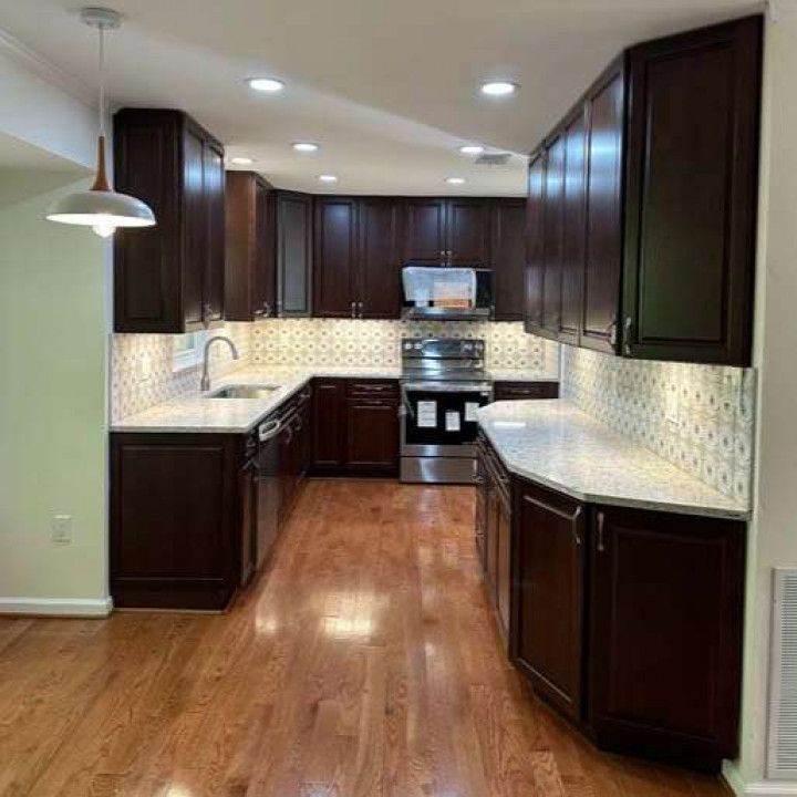 A kitchen with wooden cabinets , stainless steel appliances , granite counter tops and hardwood floors.