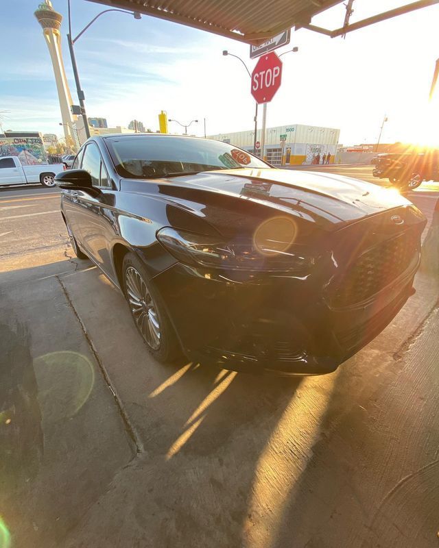 Black car parked near a stop sign, with the Stratosphere Tower visible in the background, Las Vegas, Nevada.