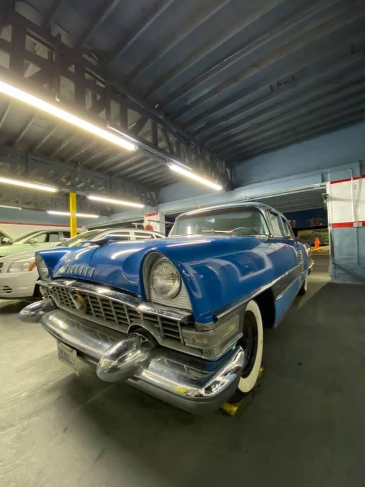 Blue classic car with white-wall tires parked inside a garage.