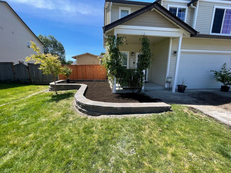 A house with a lush green lawn and a stone wall in front of it.