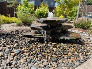 A water fountain is surrounded by rocks in a garden.