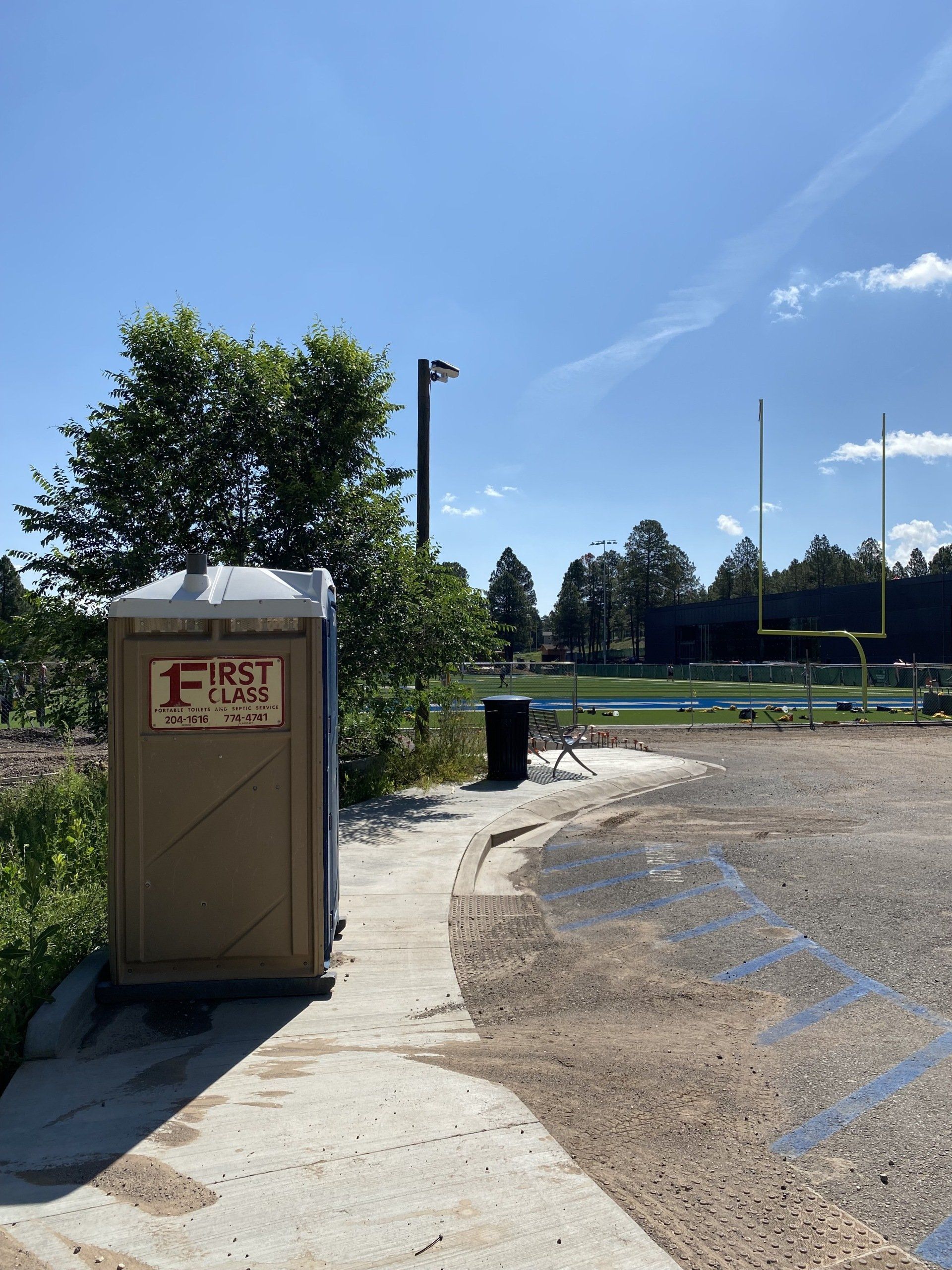 Portable restroom near a garbage bin | Flagstaff, AZ | First Class Sanitation