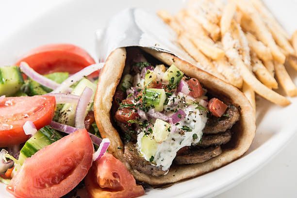 A gyro sandwich with french fries and a salad on a plate.