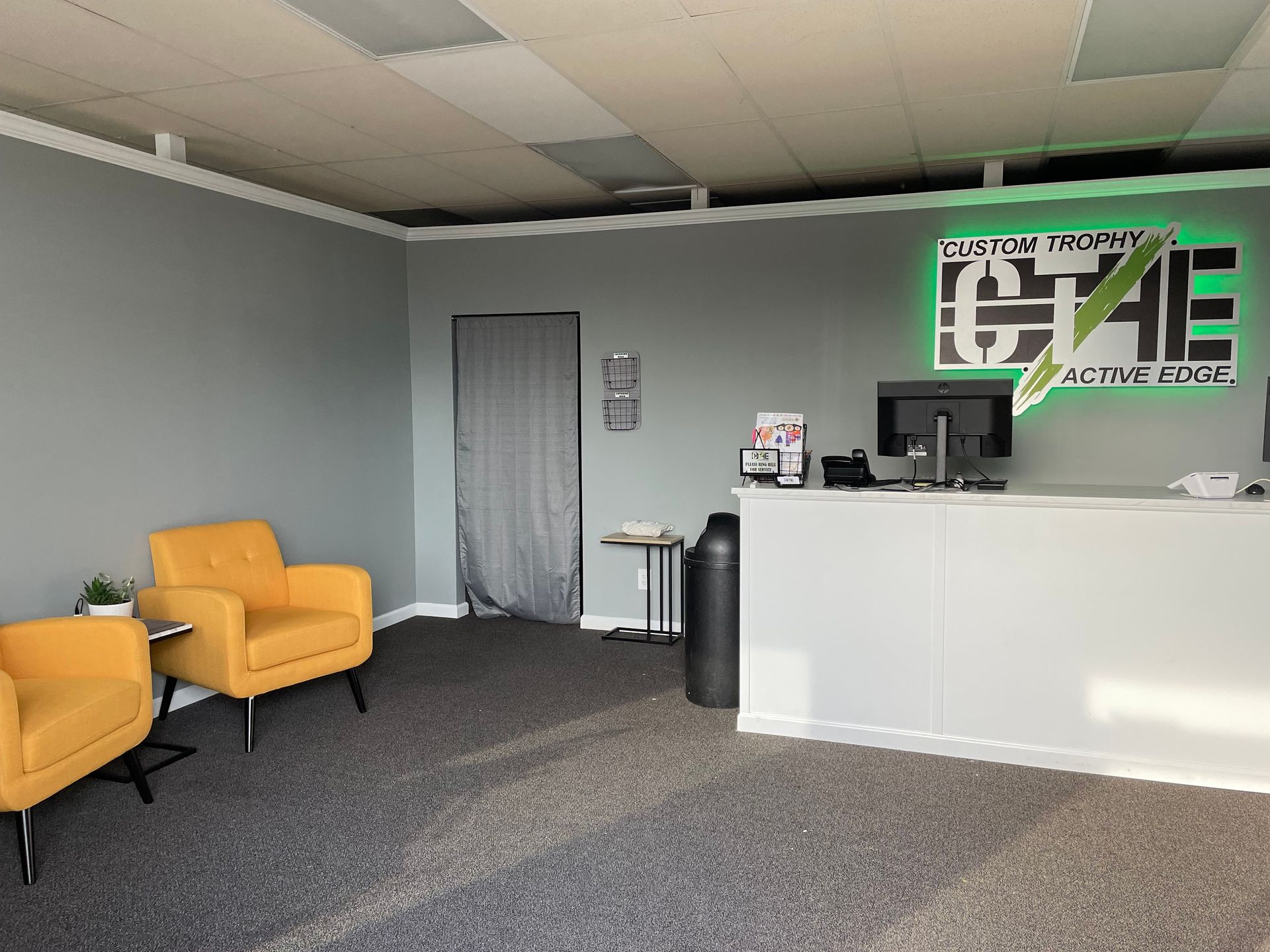 A waiting room with two yellow chairs and a desk with a green sign that says e4e