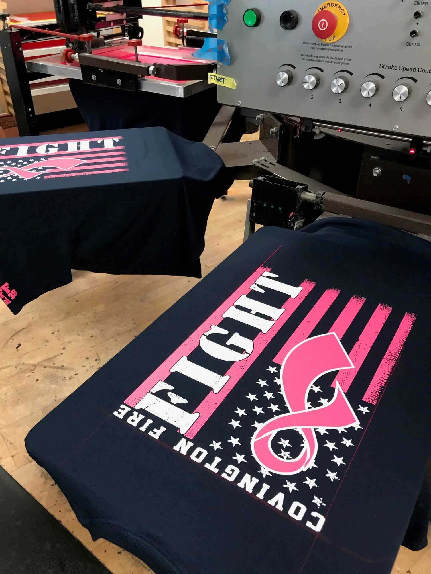 A black t-shirt with a pink breast cancer awareness logo on it