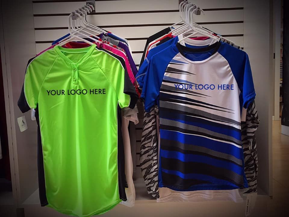 A bunch of shirts are hanging on a rack and one of them says your logo here