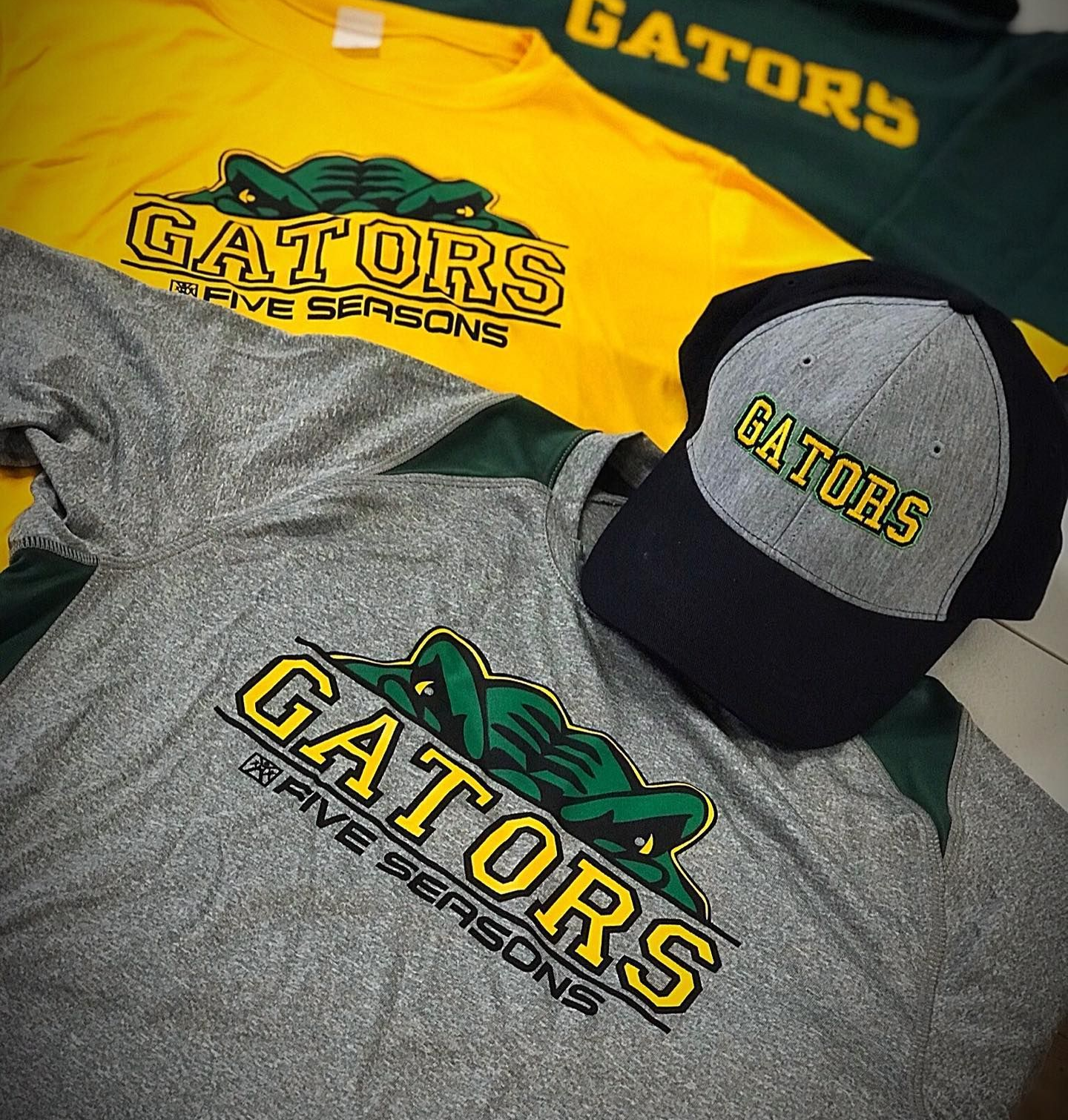 Gators sports apparel: shirts and a hat with green and yellow logo on gray, gold, and green backgrounds.