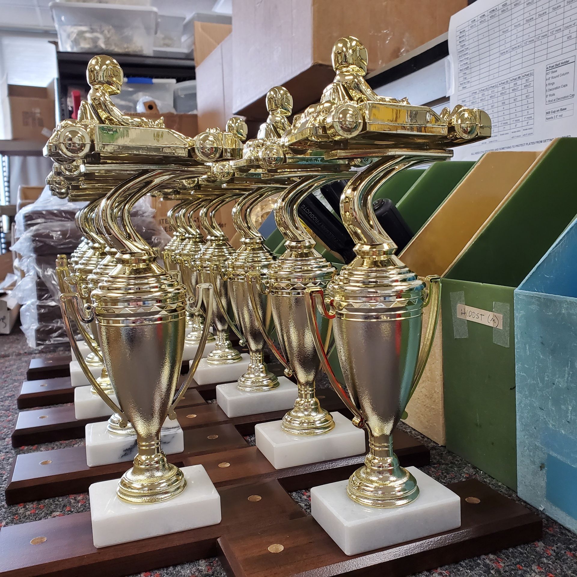 A row of gold and silver trophies are lined up on wooden bases