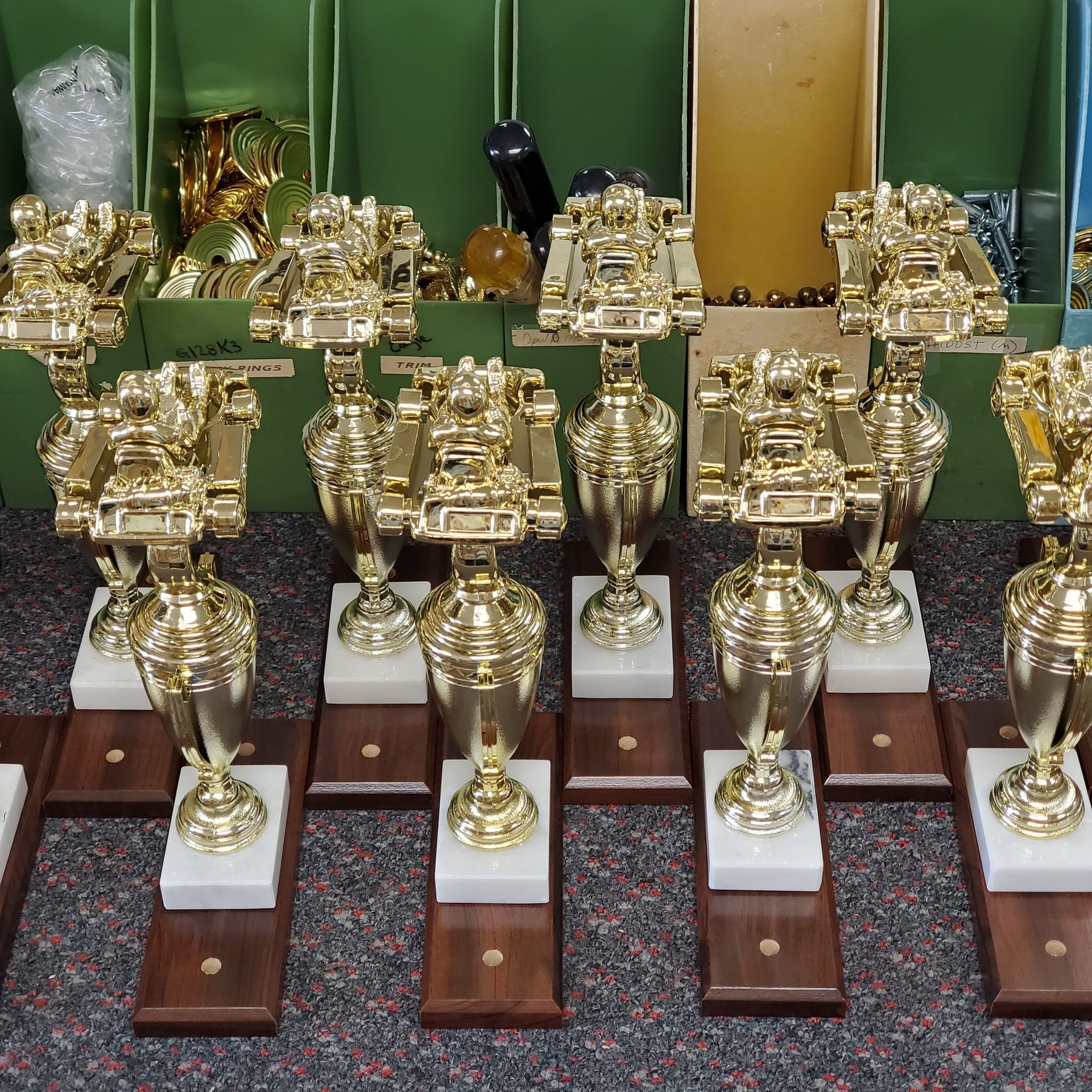 A bunch of gold trophies are lined up in a row