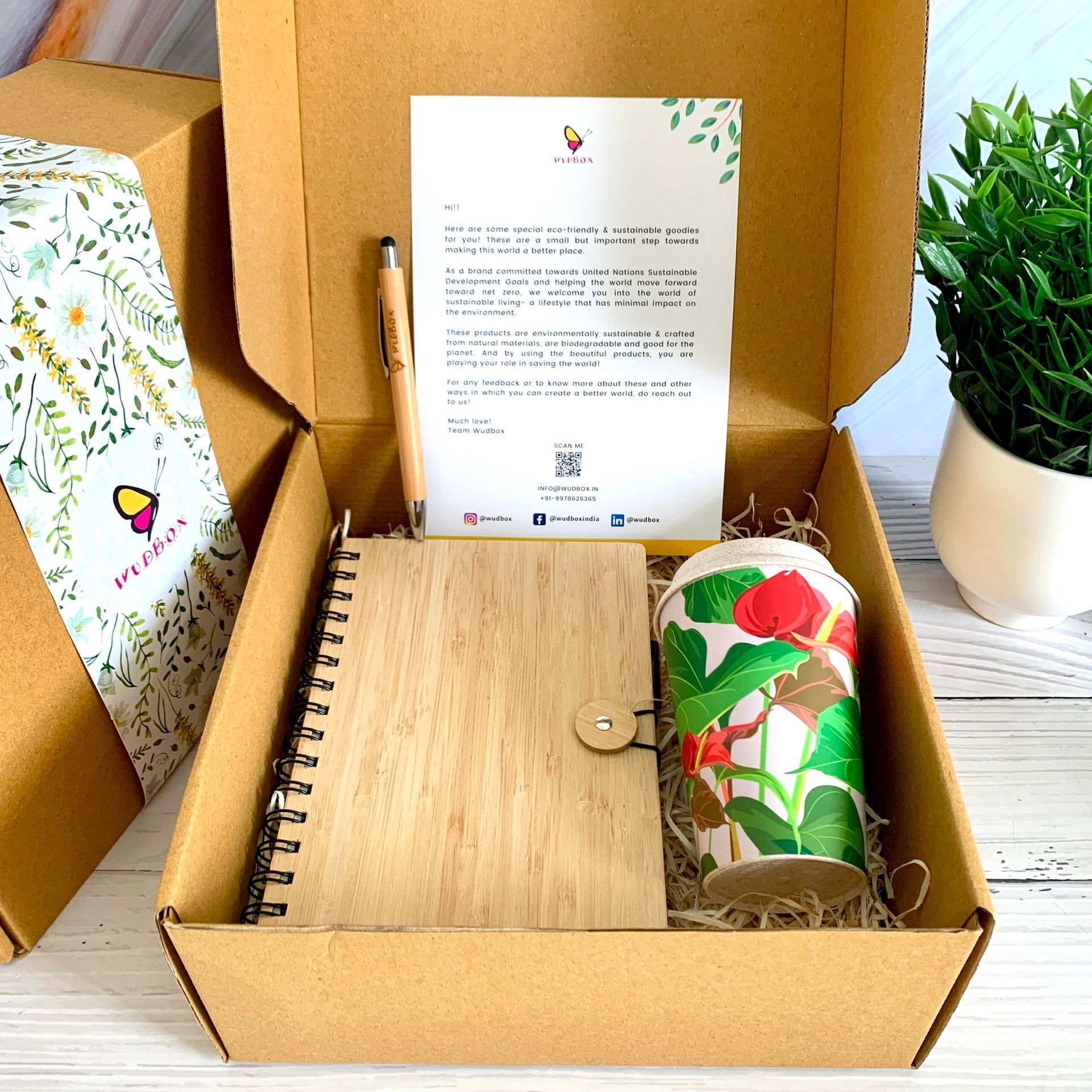 Gift box with notebook, pen, cup, and letter.