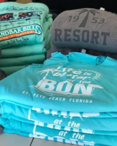 A stack of shirts with one that says life is better at the bon