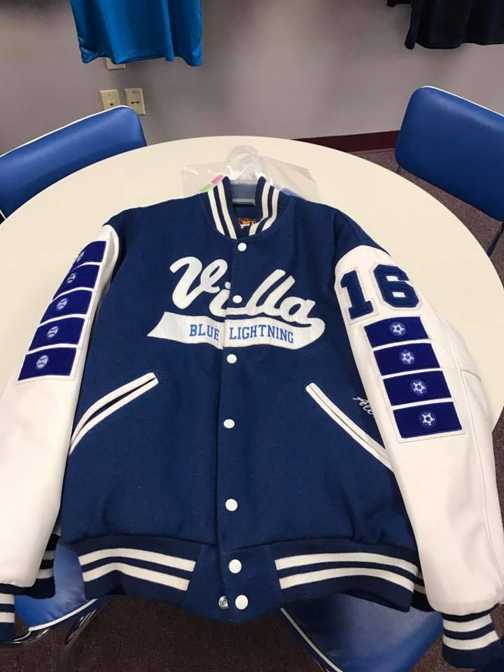A blue and white villa varsity jacket is sitting on a table