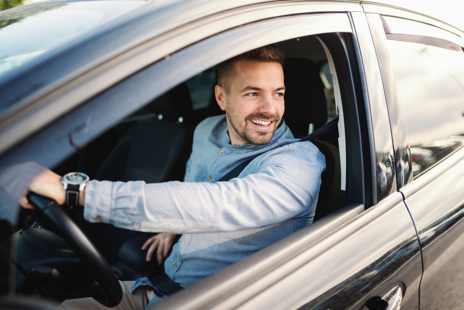 Man smiling, driving a black car