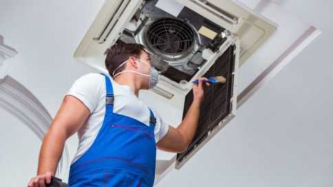 a man wearing a mask is working on an air conditioner .