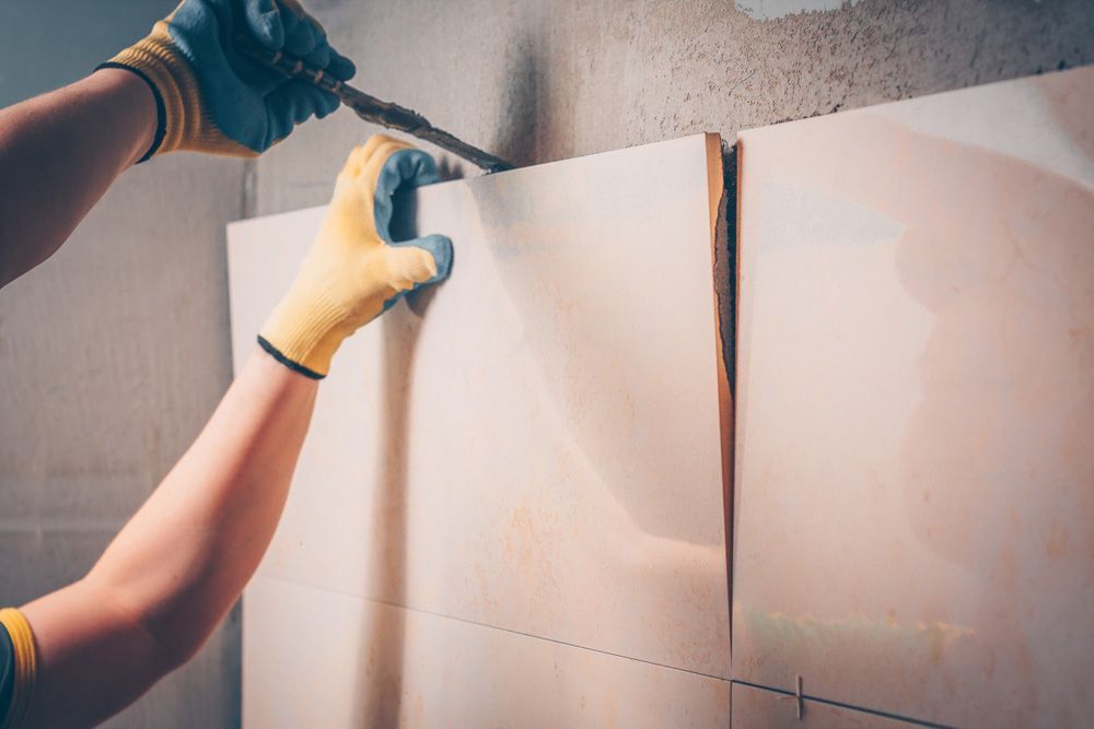 A Person Is Frying Up A Piece Of Tile — Custom Design Bathroom Renovations in Wauchope, NSW