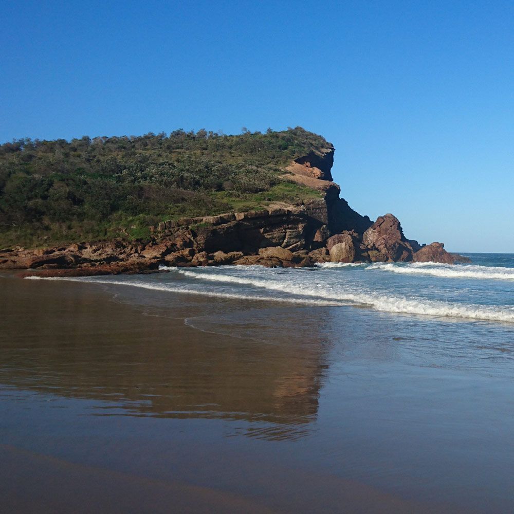 A Beach With A Large Cliff Beside It — Custom Design Bathroom Renovations in Bonny Hills, NSW