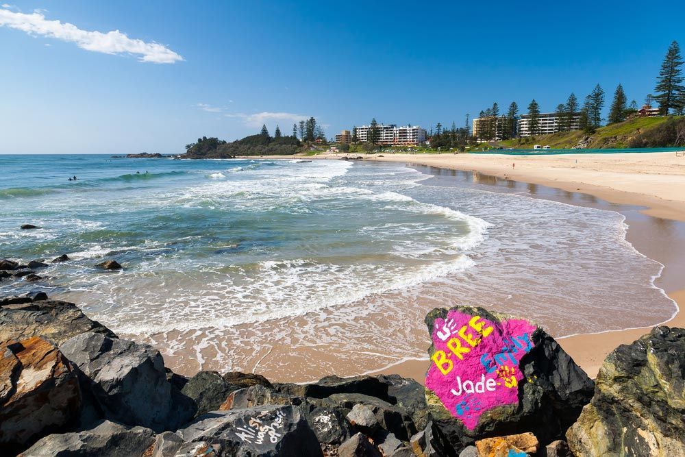 A Beach With A Pink Rock In The Foreground That Says Jade On It — Custom Design Bathroom Renovations in Port Macquarie, NSW