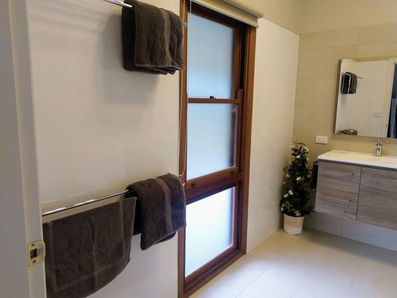 A Bathroom With Towels Hanging On A Towel Rack And A Sink — Custom Design Bathroom Renovations in Port Macquarie, NSW