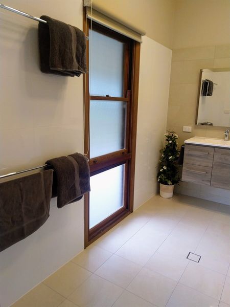 A Bathroom With Towels Hanging On The Wall And A Window — Custom Design Bathroom Renovations in Port Macquarie, NSW