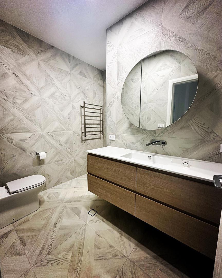 A Bathroom With A Toilet, Sink, Mirror And Towel Rack — Custom Design Bathroom Renovations in Port Macquarie, NSW