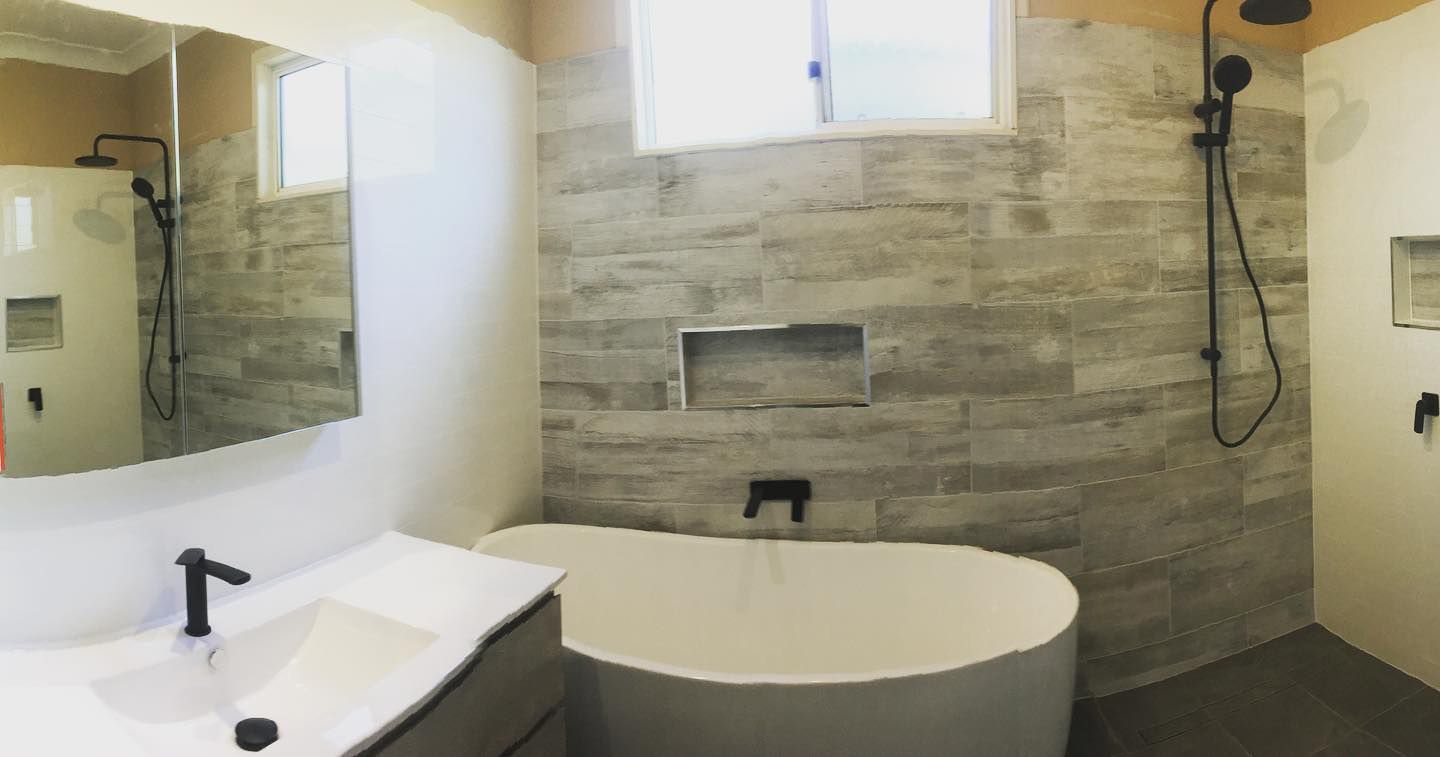 A Bathroom With A Tub, Sink, Mirror And Shower — Custom Design Bathroom Renovations in Port Macquarie, NSW