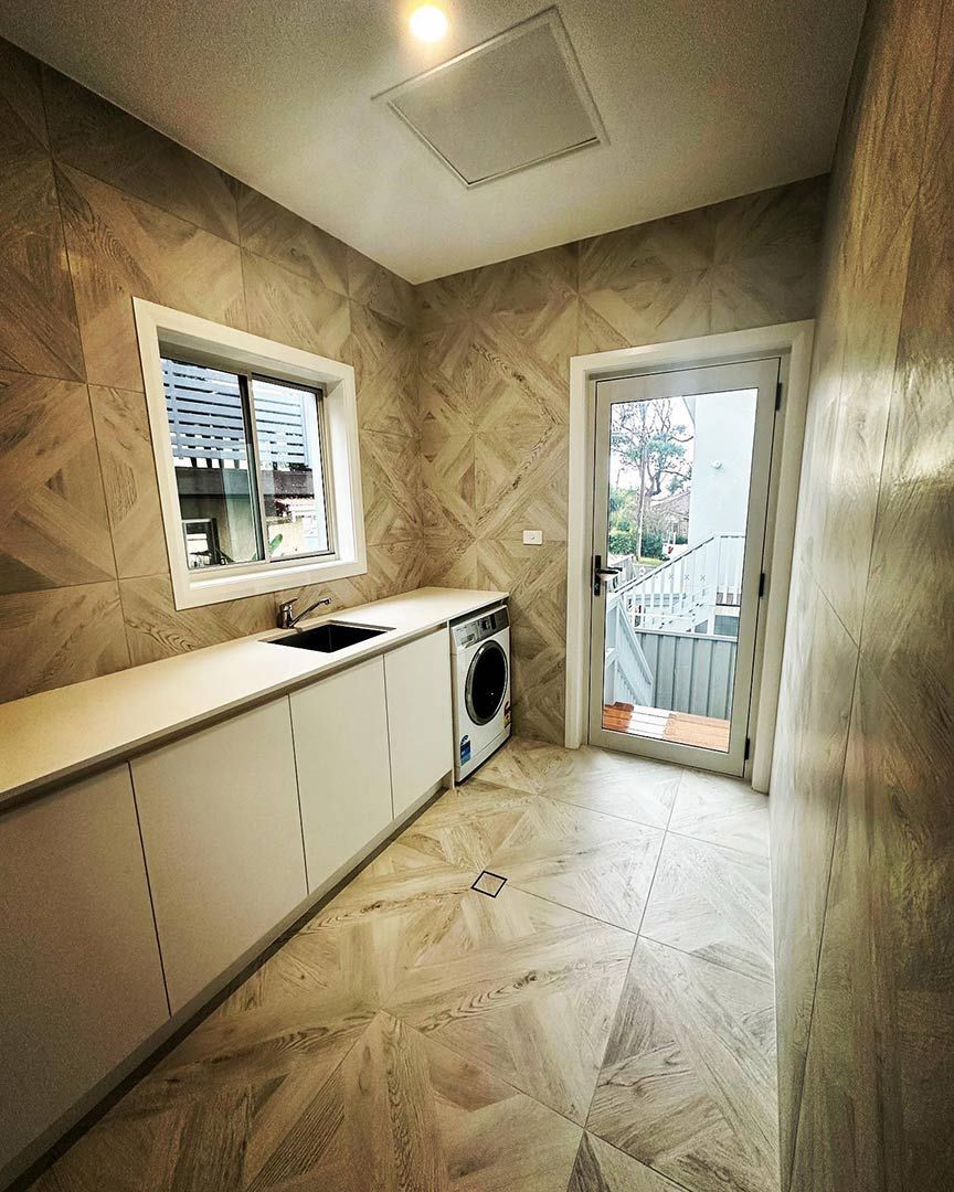 A Laundry Room With A Washing Machine, Sink, And Window — Custom Design Bathroom Renovations in Port Macquarie, NSW