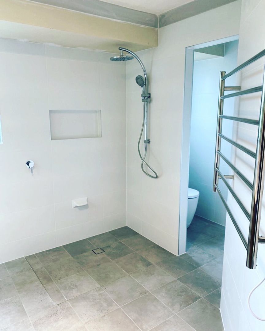 A Bathroom With A Walk In Shower, Toilet And Towel Rack — Custom Design Bathroom Renovations in Port Macquarie, NSW