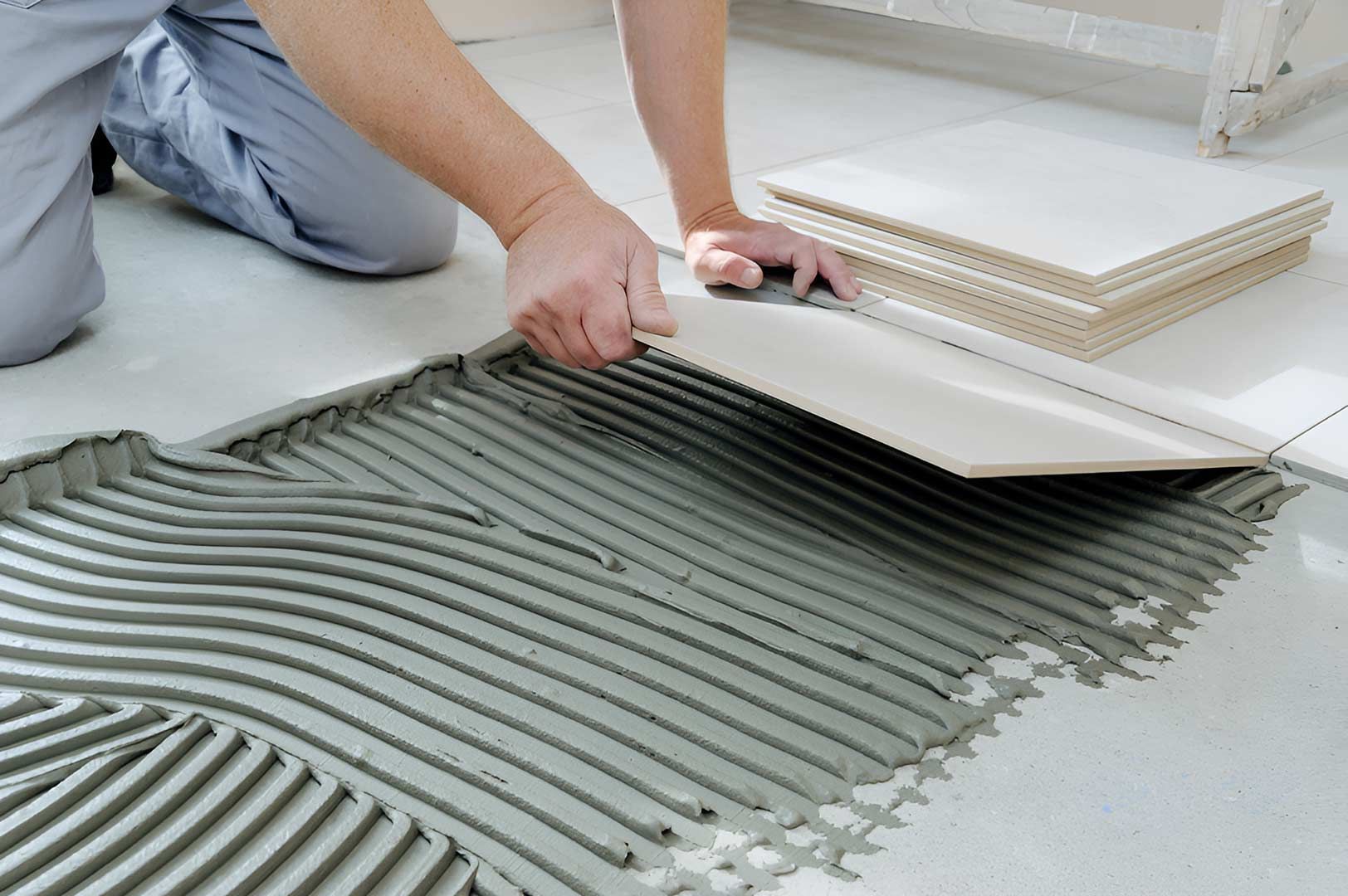 A Person Is Laying Tiles On A Tiled Floor — Custom Design Bathroom Renovations in Port Macquarie, NSW