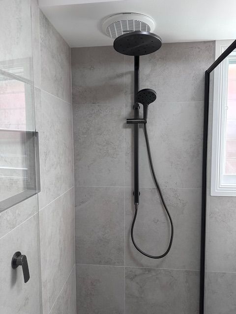 Black Showerhead With Handheld Sprayer Against Gray Tiled Wall — Custom Design Bathroom Renovations in Port Macquarie, NSW