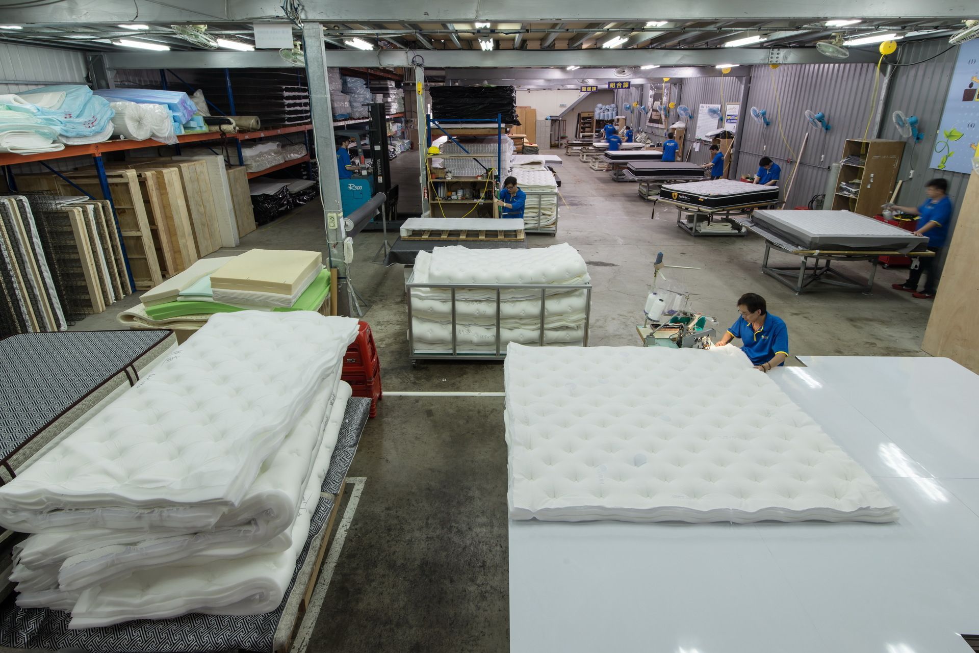 倉庫裡堆滿了床墊，還有人在處理它們。