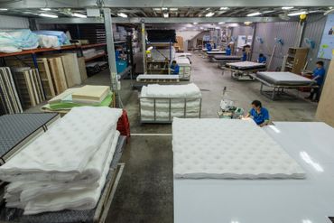 倉庫裡堆滿了床墊，還有人在處理它們。