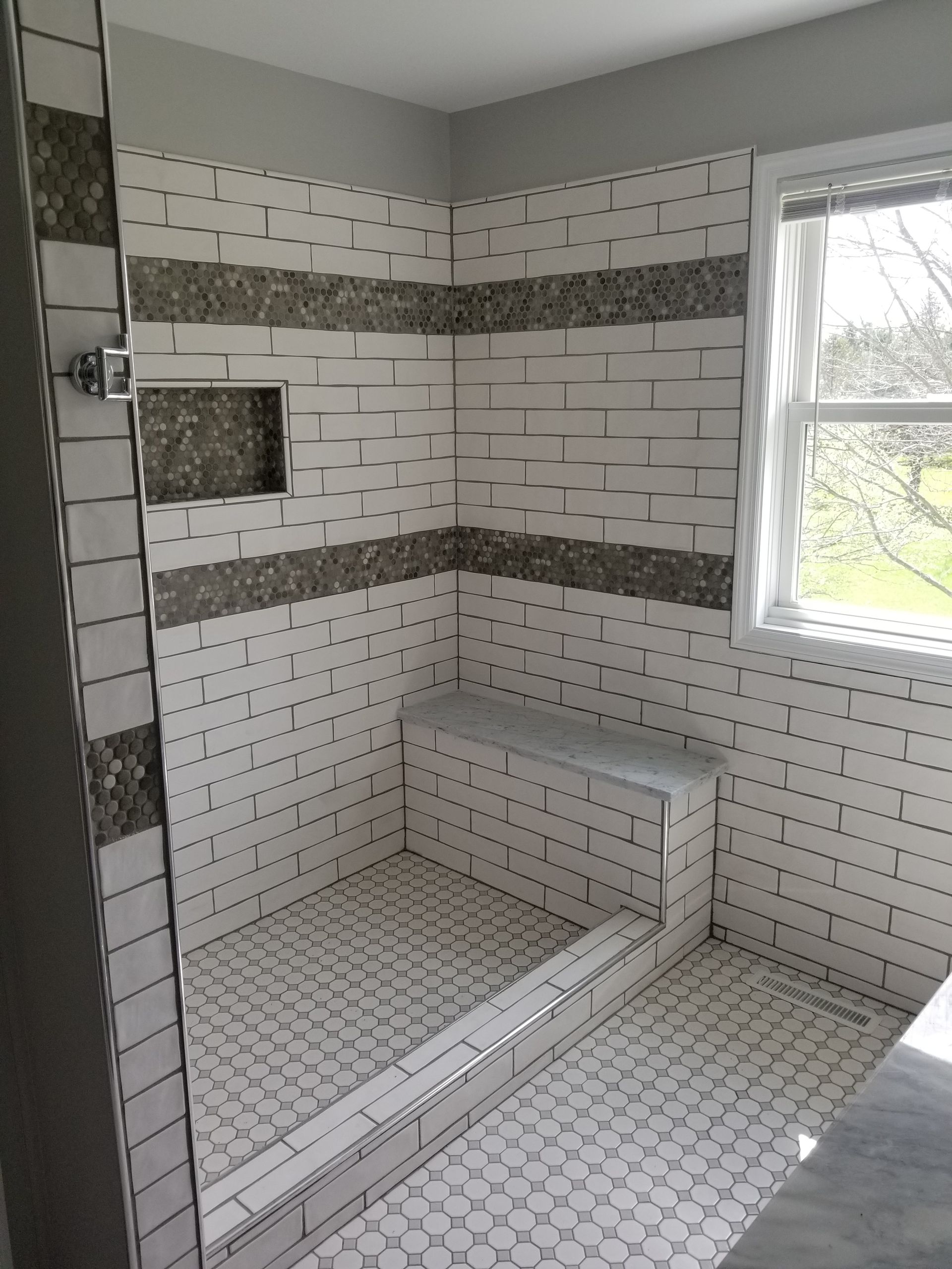 A bathroom with a walk in shower and a window.