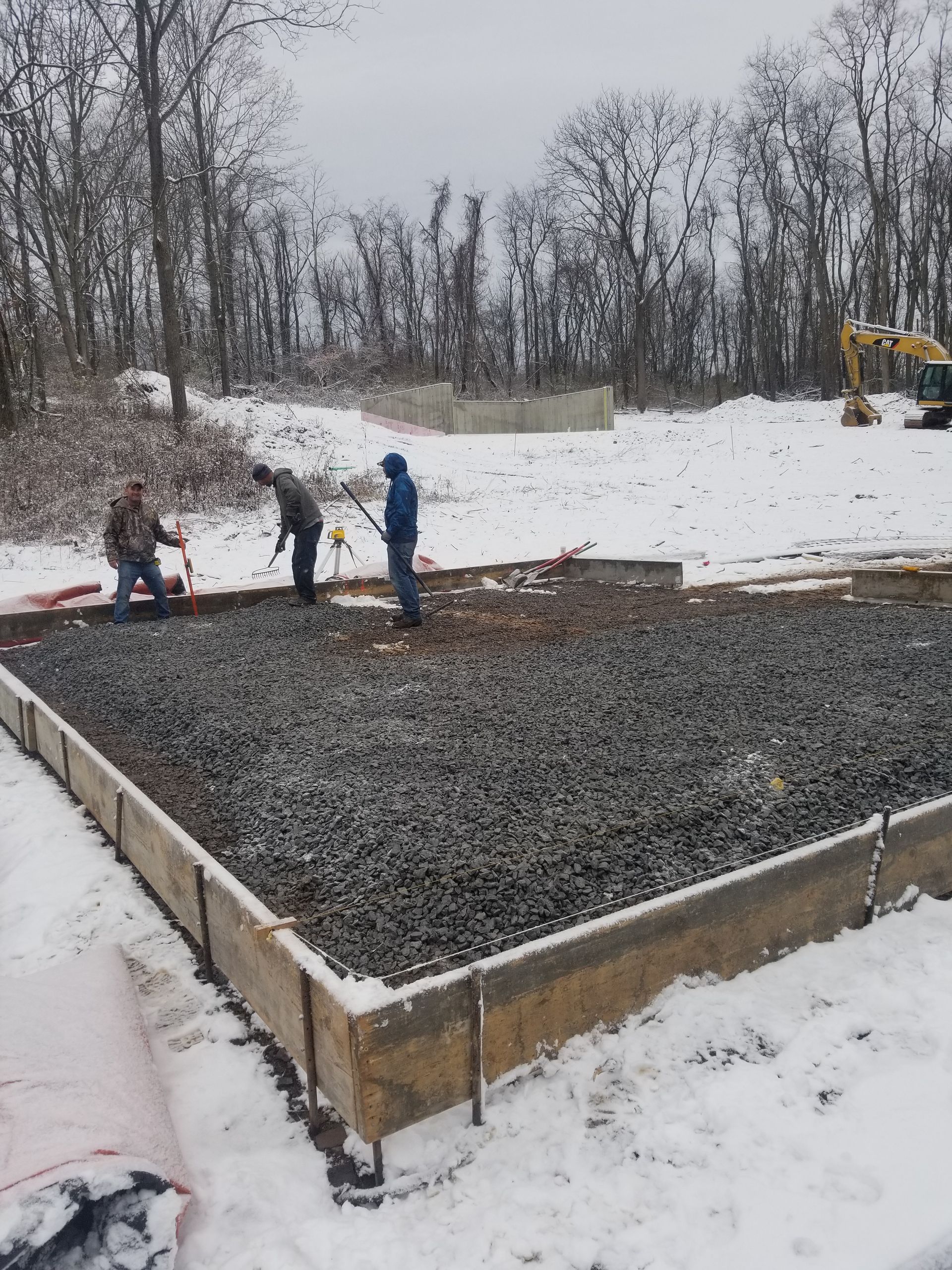 A group of people are working on a construction site in the snow.