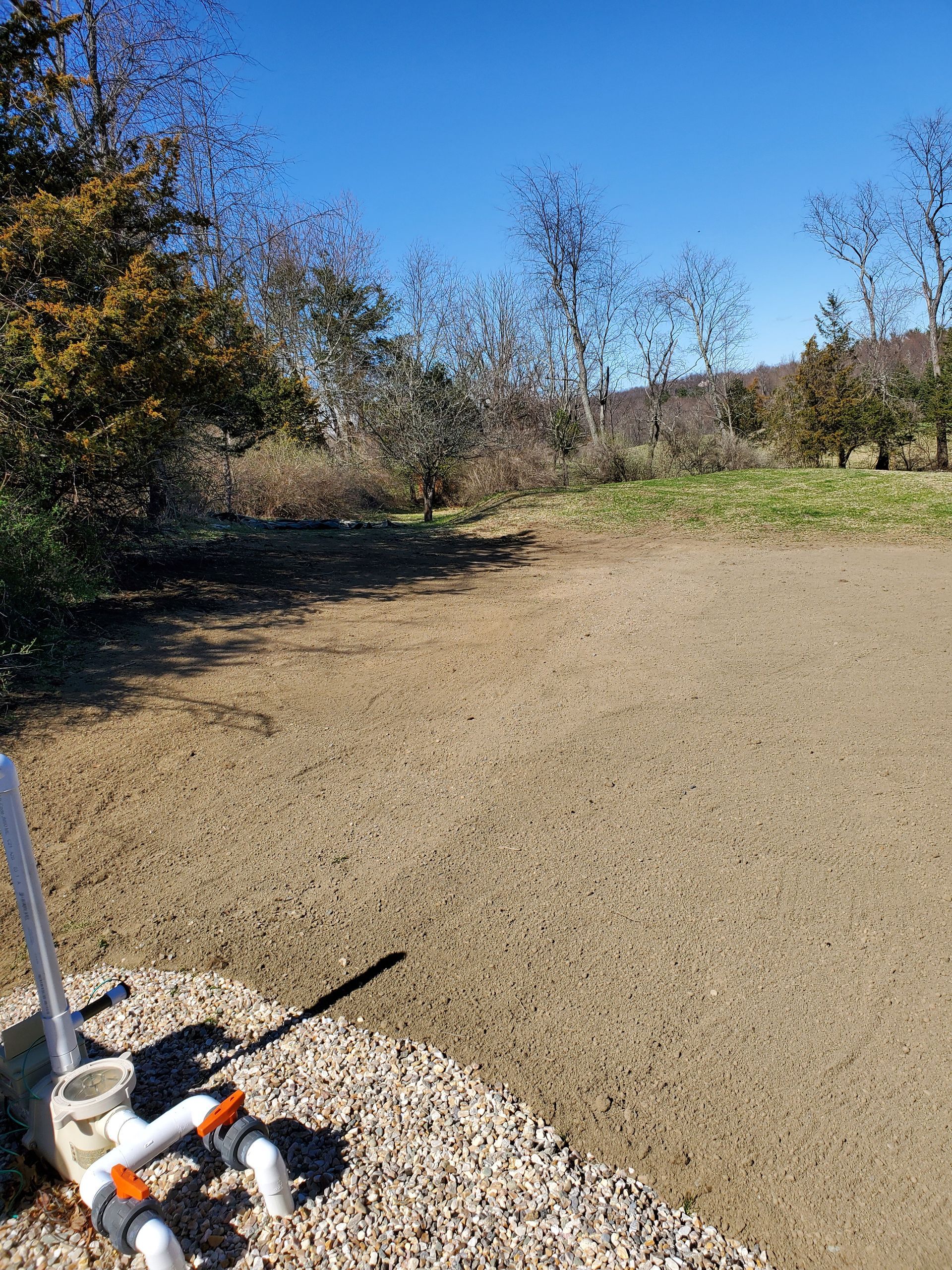 A group of pipes are sitting on top of a pile of gravel in a field.