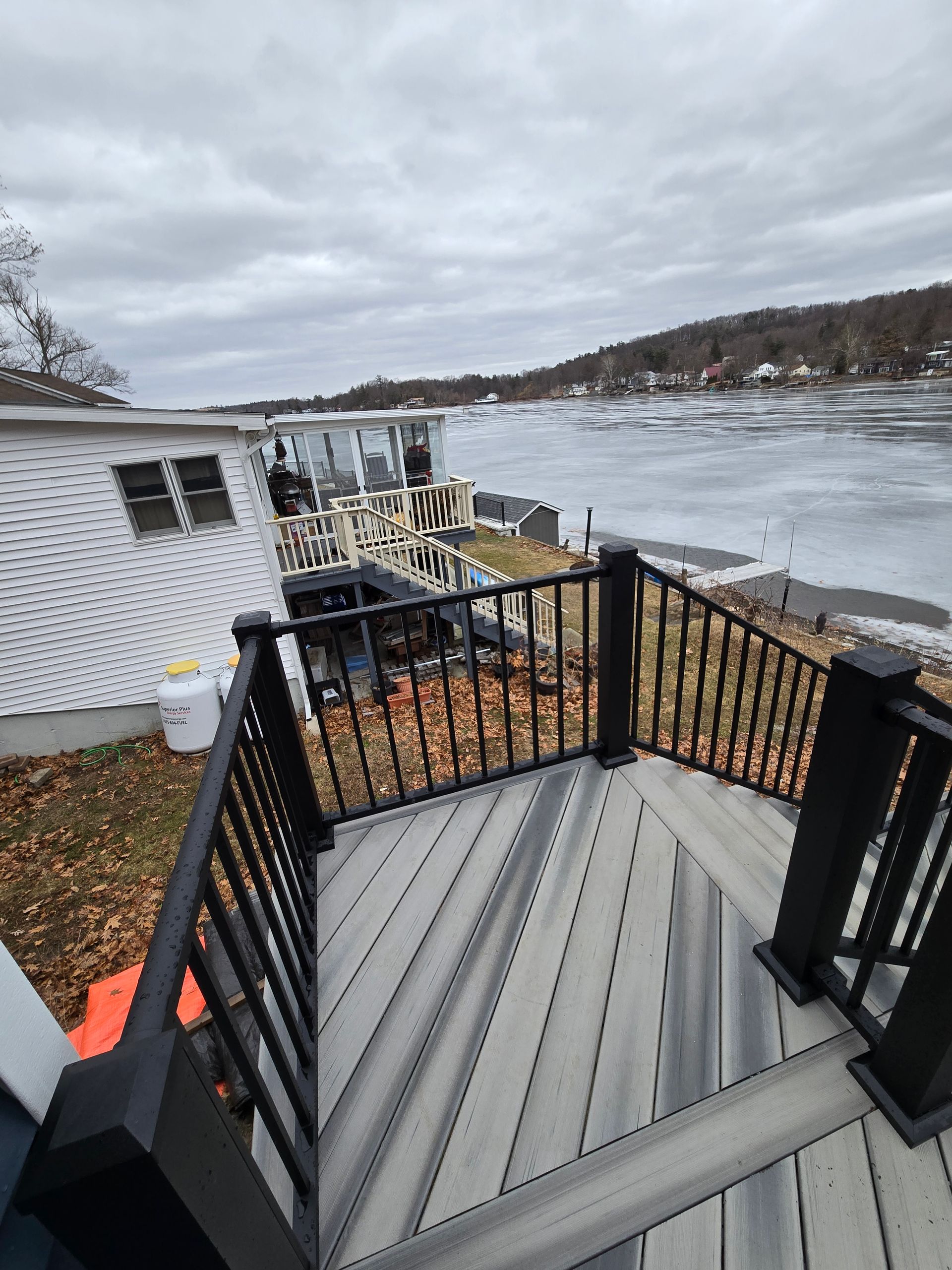 A deck with stairs leading up to the water and a house in the background.