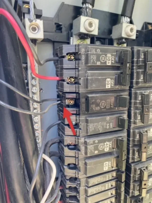 A close up of a electrical box with a red arrow pointing to a breaker.