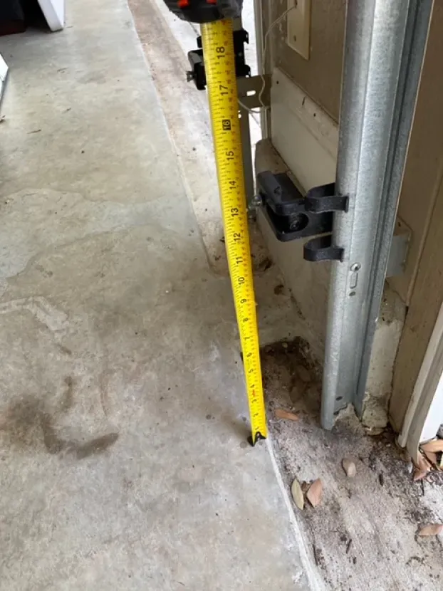 A yellow tape measure is being used to measure the height of a garage door.