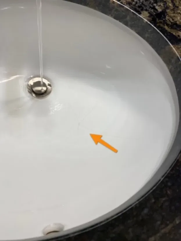 A white sink with an orange arrow pointing to the drain.
