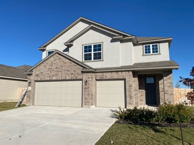 A white house with a brick facade and two garage doors