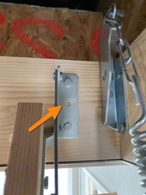 An arrow points to a screw on a piece of wood