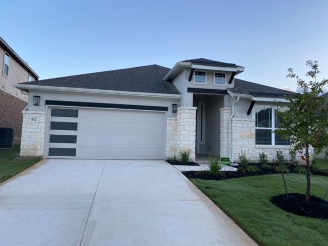 A white house with a black roof and a concrete driveway