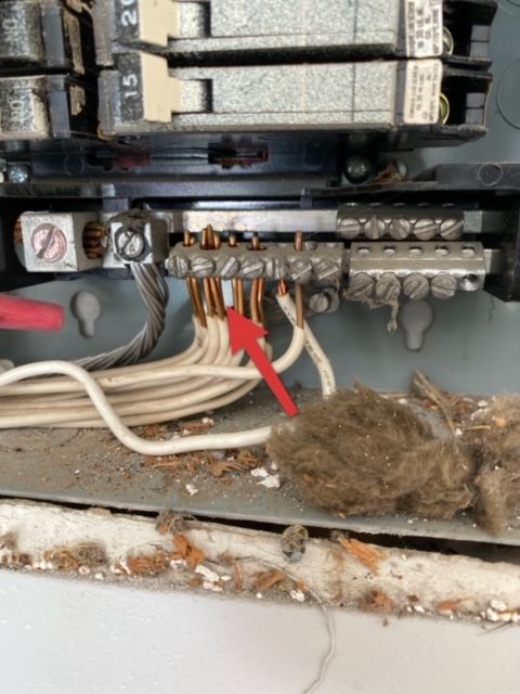 A dirty electrical box with a red arrow pointing to a wire