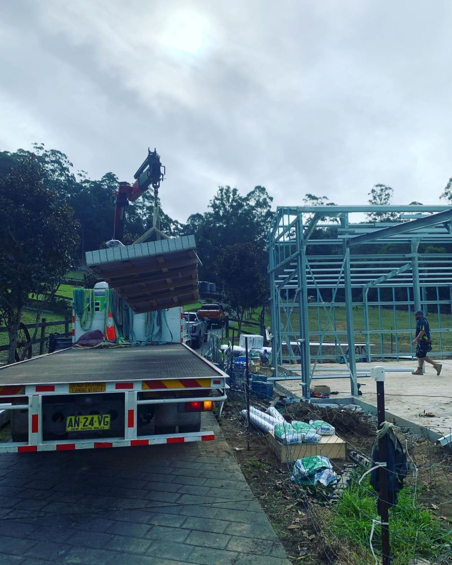 A Crane Lifts Concrete Panels from A Flatbed Truck at A Construction Site — Express Timber Solutions In Long Jetty, NSW