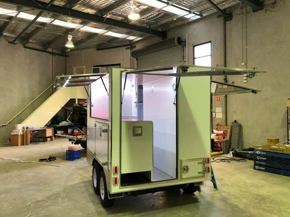 A White Trailer Is Parked In A Warehouse With The Door Open — Robon Electrical In Holloways Beach, QLD