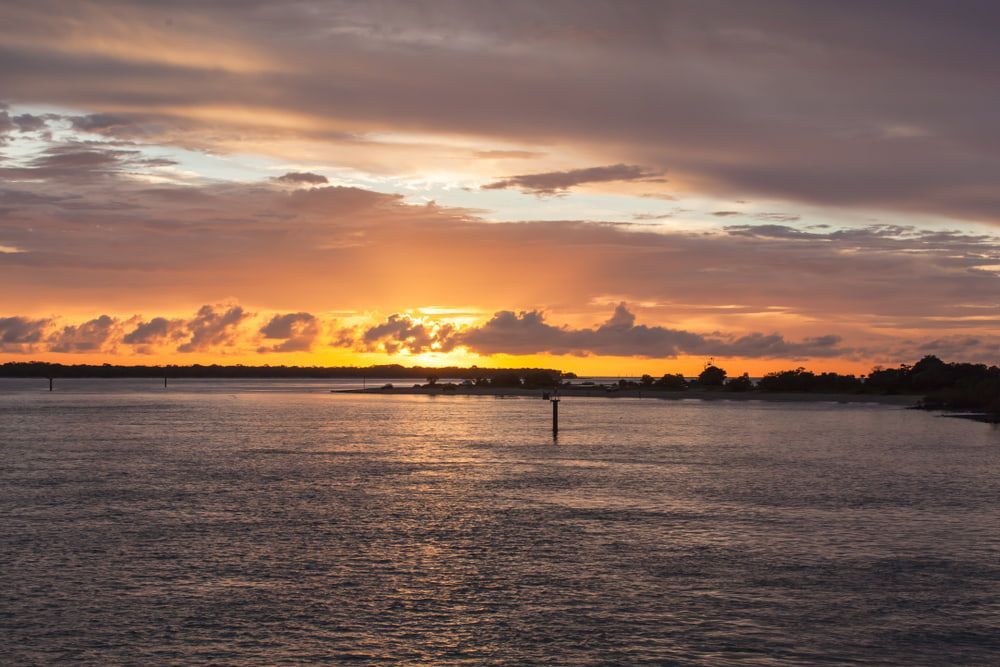 A Sunset Over A Body Of Water With Clouds In The Sky — Robon Electrical In Weipa, QLD
