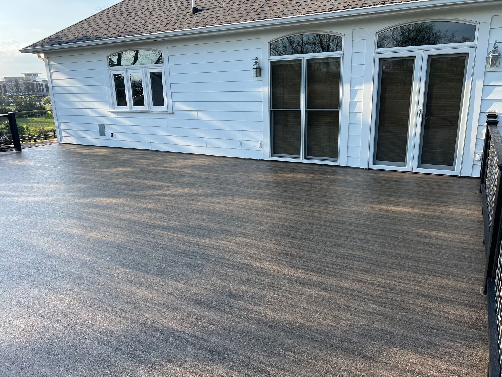 A composite deck outside a white house with sliding glass doors.