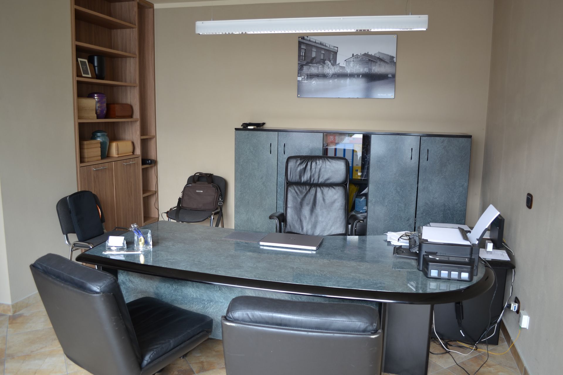 Un ufficio con una grande scrivania e sedie e un dipinto sul muro