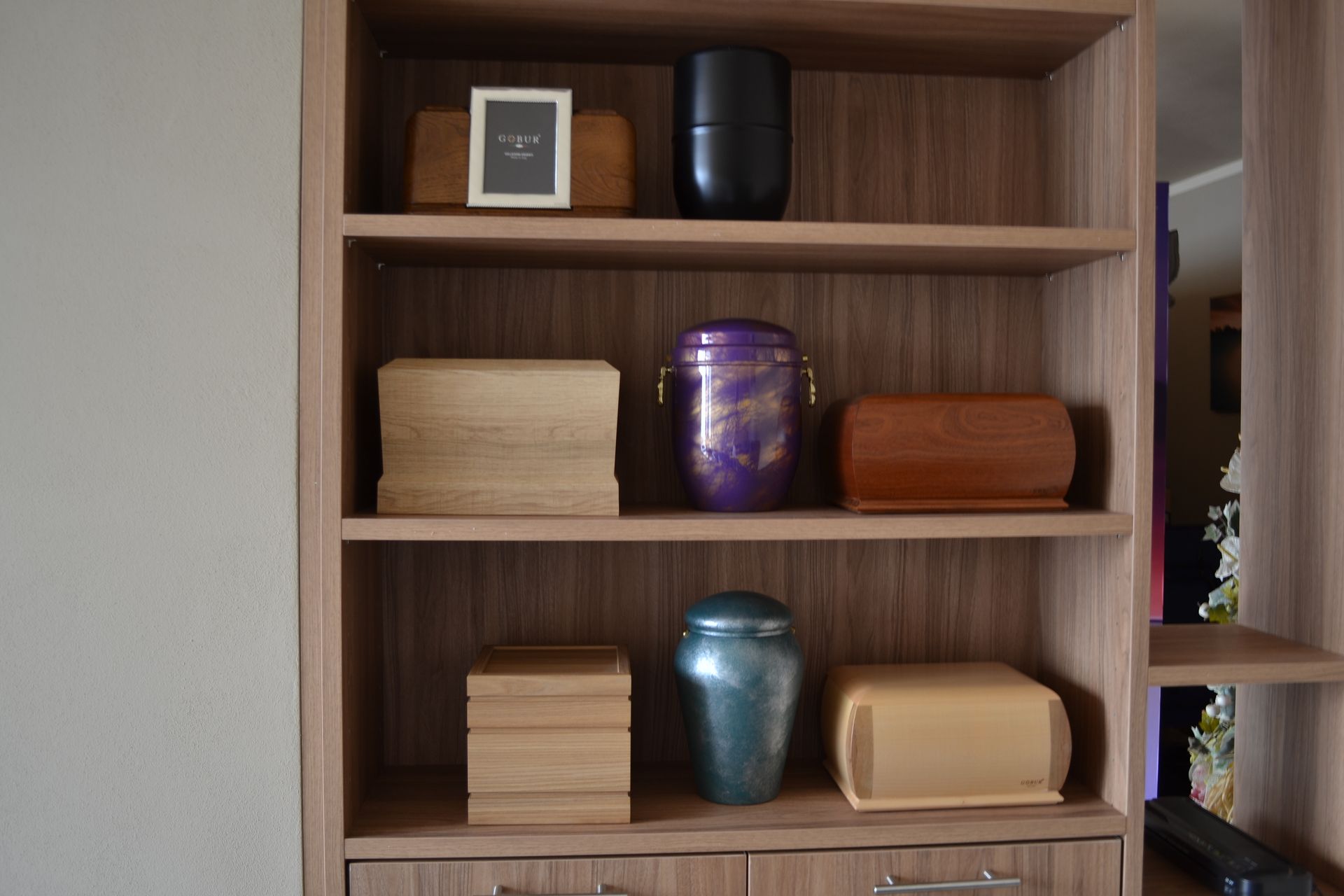 Uno scaffale di legno con urne e scatole sopra